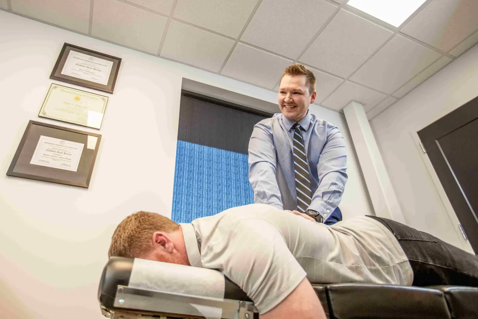 Chiropractor adjusting the back of a man lying face down on a table