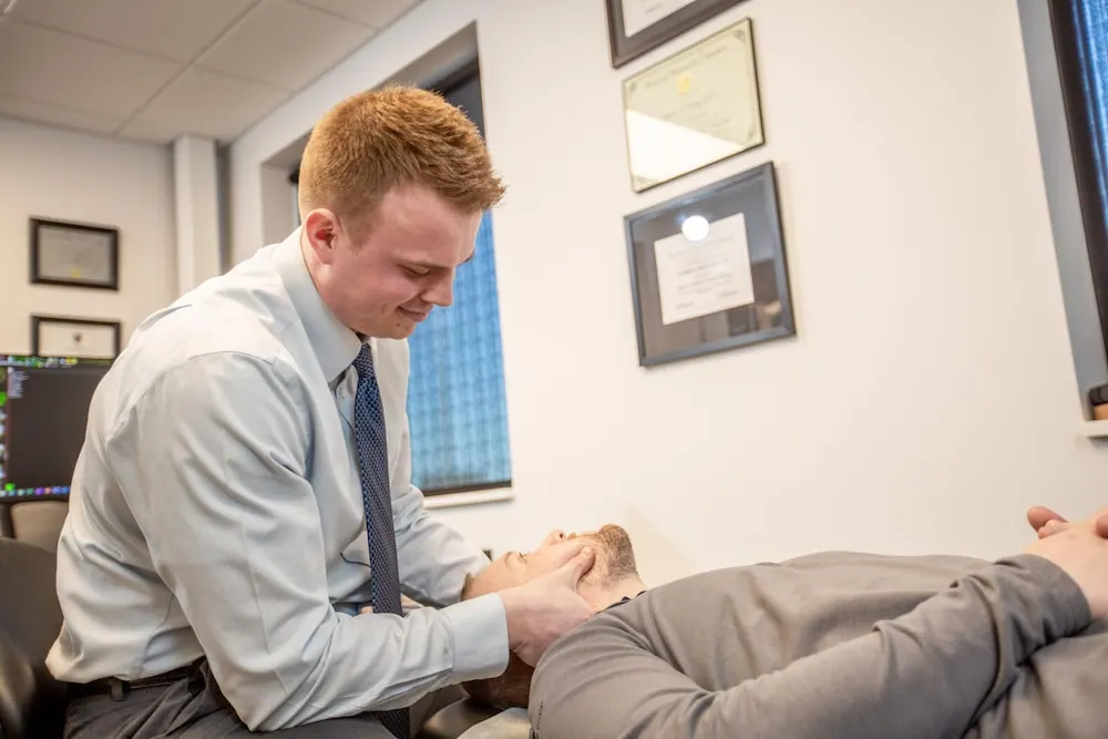 Chiropractor adjusting the neck of a patient lying on a treatment table