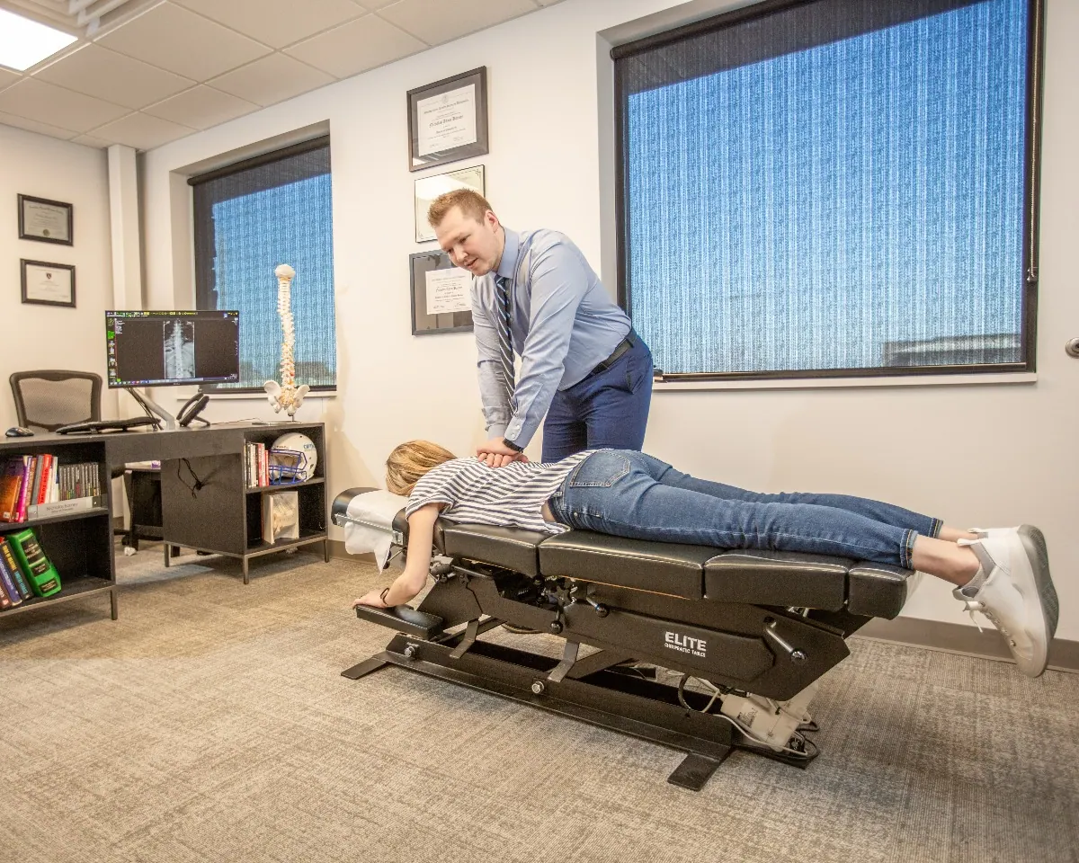 Chiropractor adjusting a patient lying face down on a chiropractic table