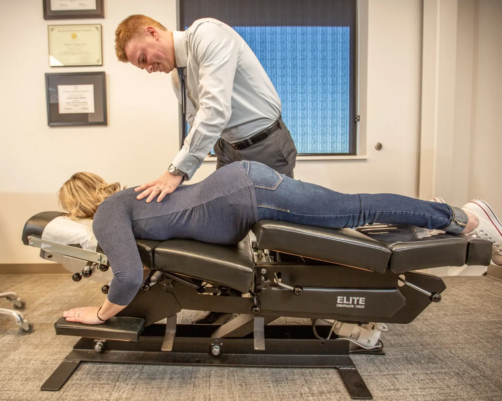 Chiropractor adjusting a woman lying face down on a chiropractic table