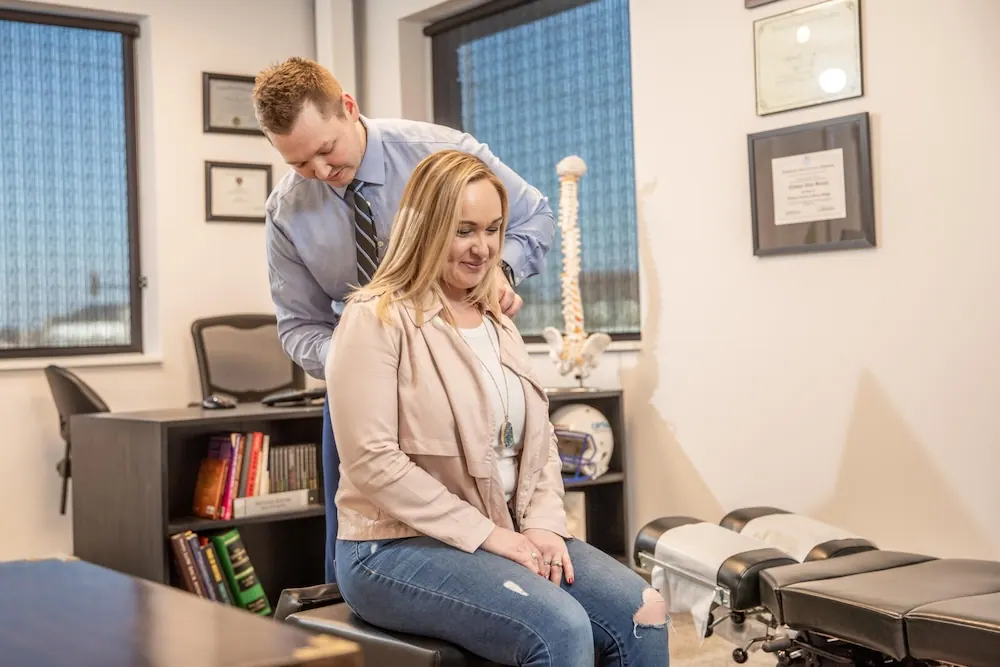 Chiropractor examining the shoulder of a seated female patient