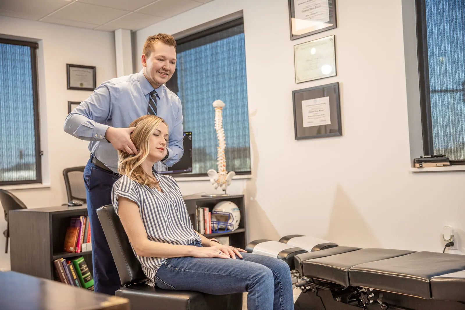 Chiropractor examining the shoulder of a seated female patient