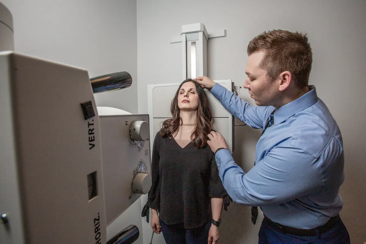 Chiropractor positioning a woman at an X-ray machine
