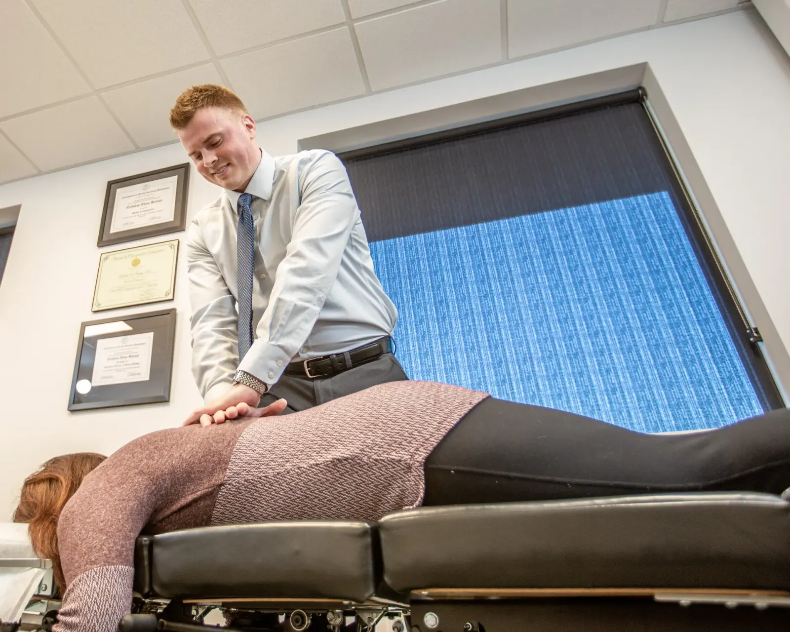 Chiropractor performing a spinal adjustment on a woman lying face down