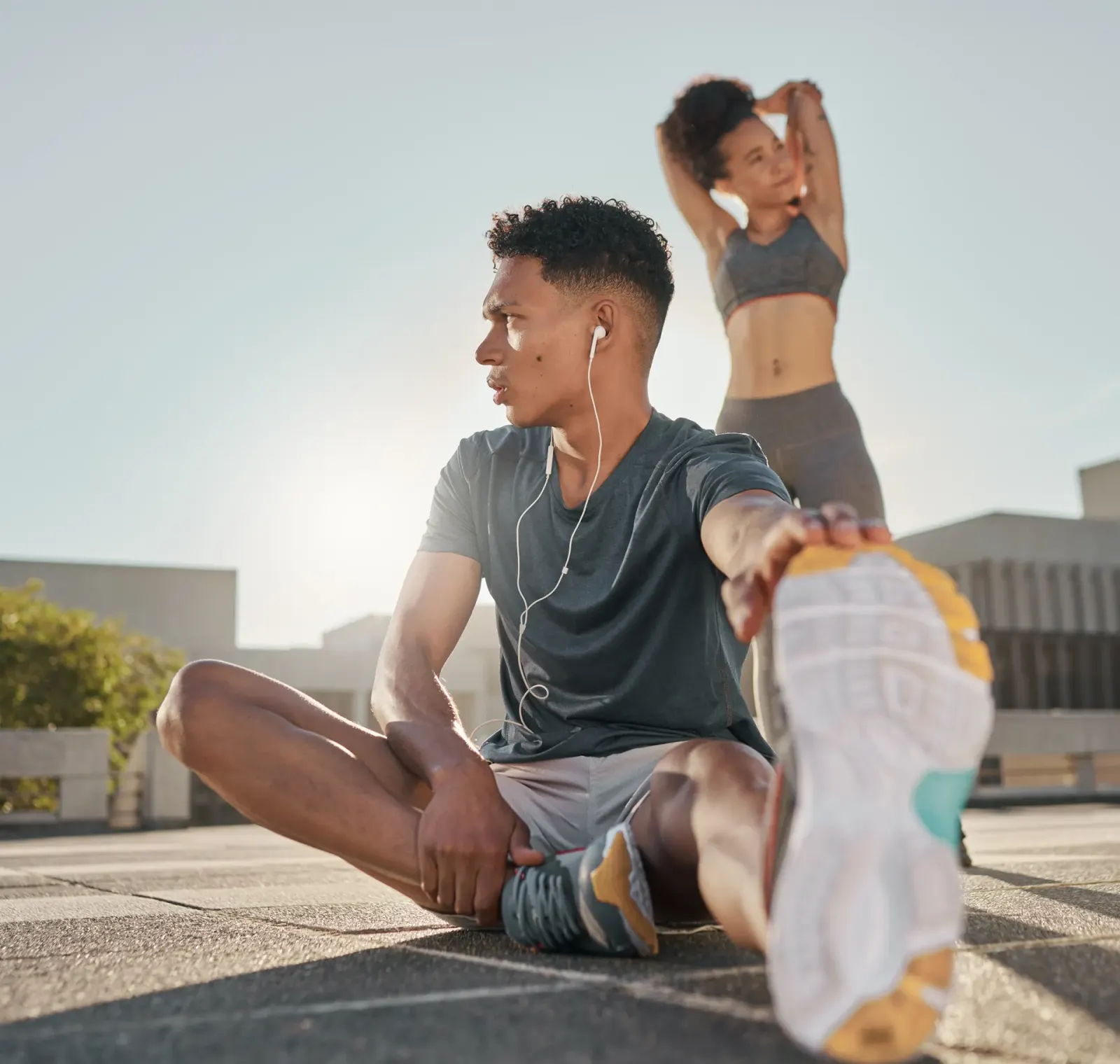 Man and woman stretching outdoors on a city rooftop