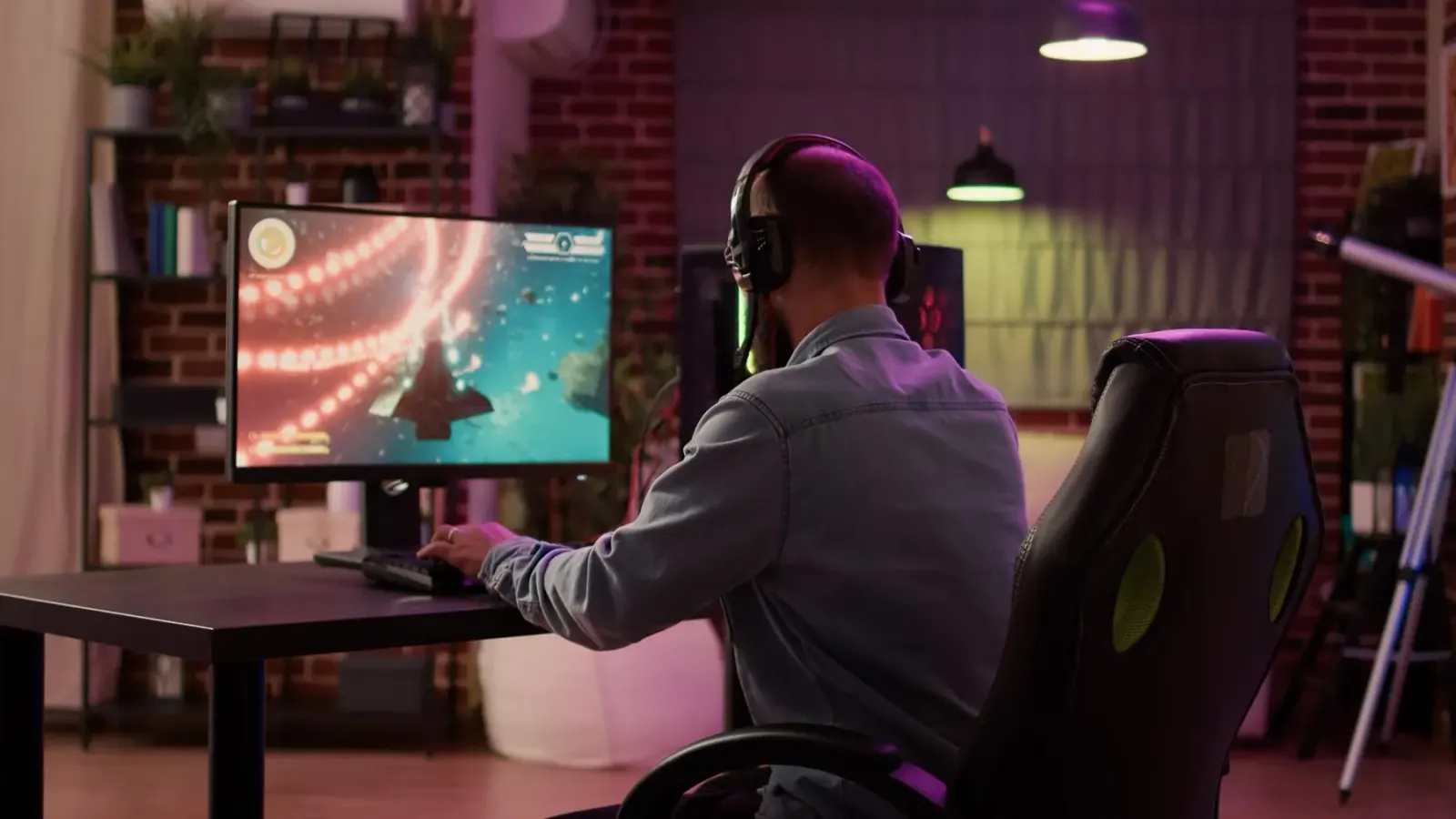 Man wearing a headset playing a game at a PC