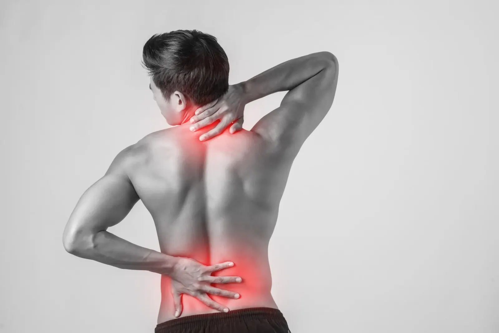 Shirtless man rubbing his back with painful areas highlighted in red