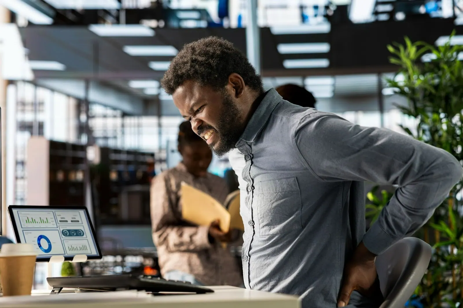 Man in an office holding his lower back