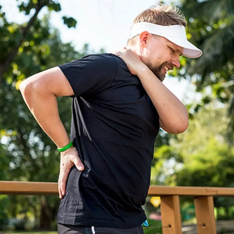 Man outdoors holding his neck and lower back