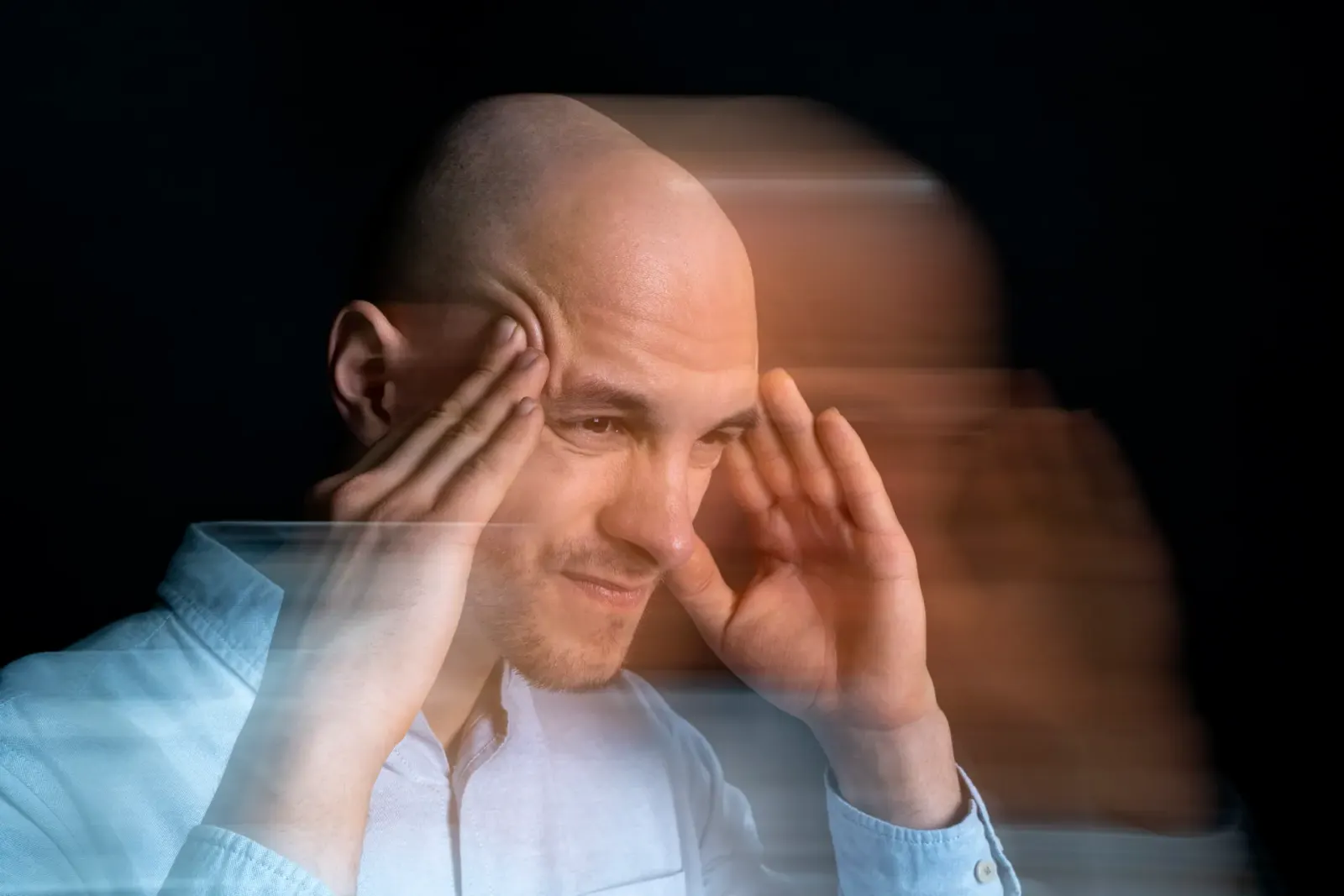 Man holding his head with a blurred, dizzy effect