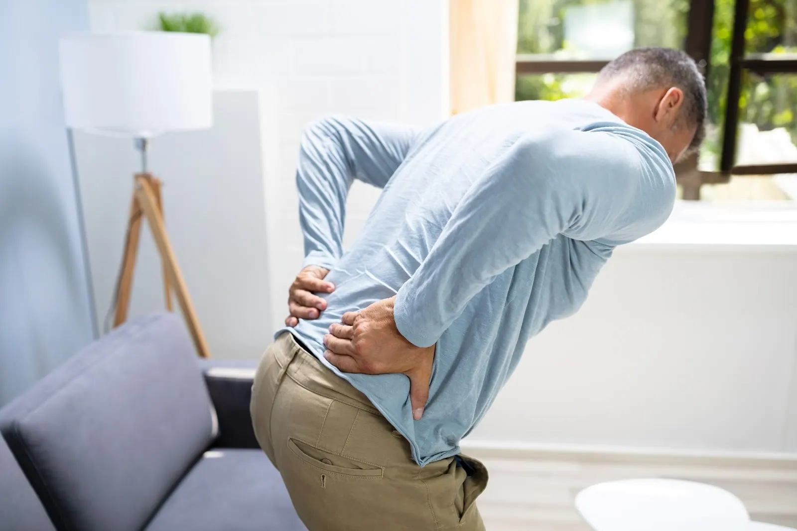 Man at home holding his lower back