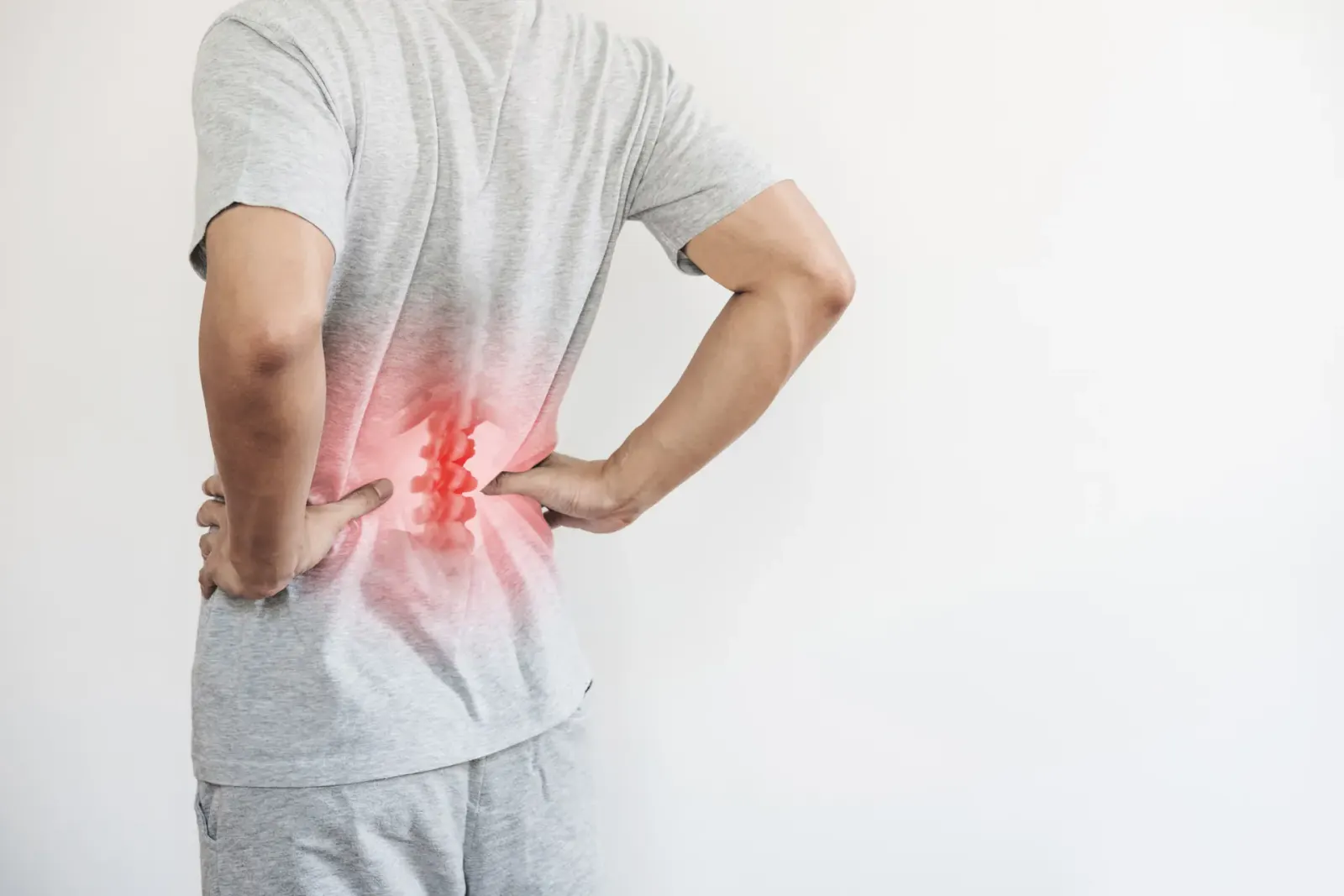 Man holding his lower back with the painful area highlighted in red