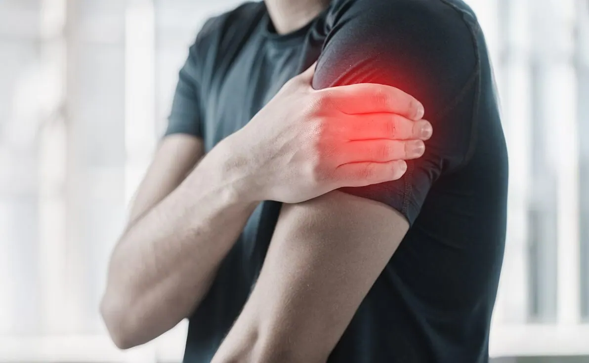 Man holding his upper arm with the painful area highlighted in red