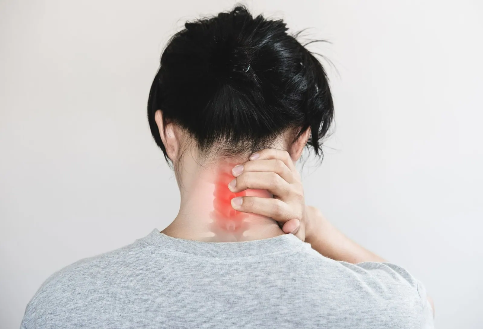 Person holding the back of their neck with the painful area highlighted