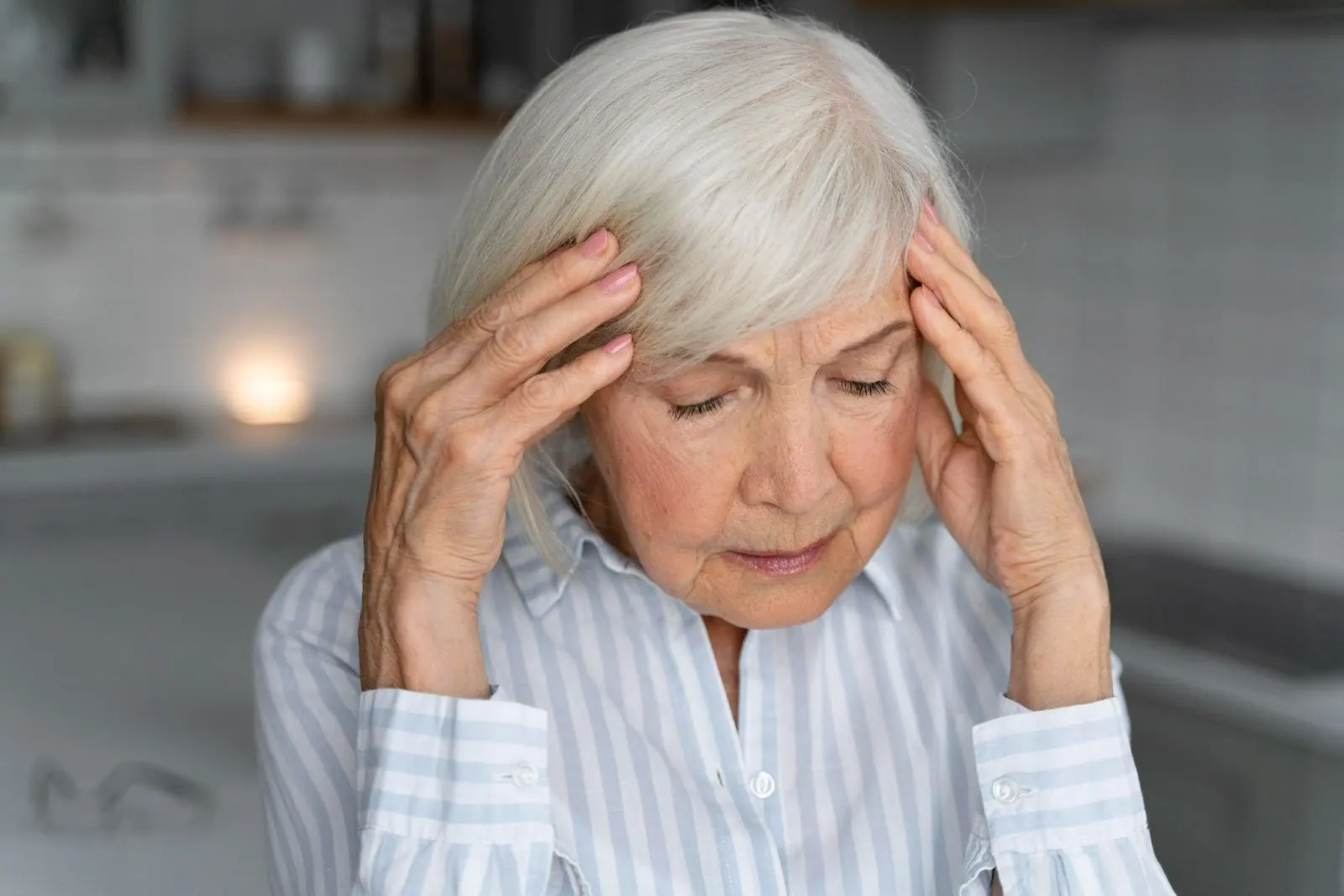Older woman holding her head with both hands