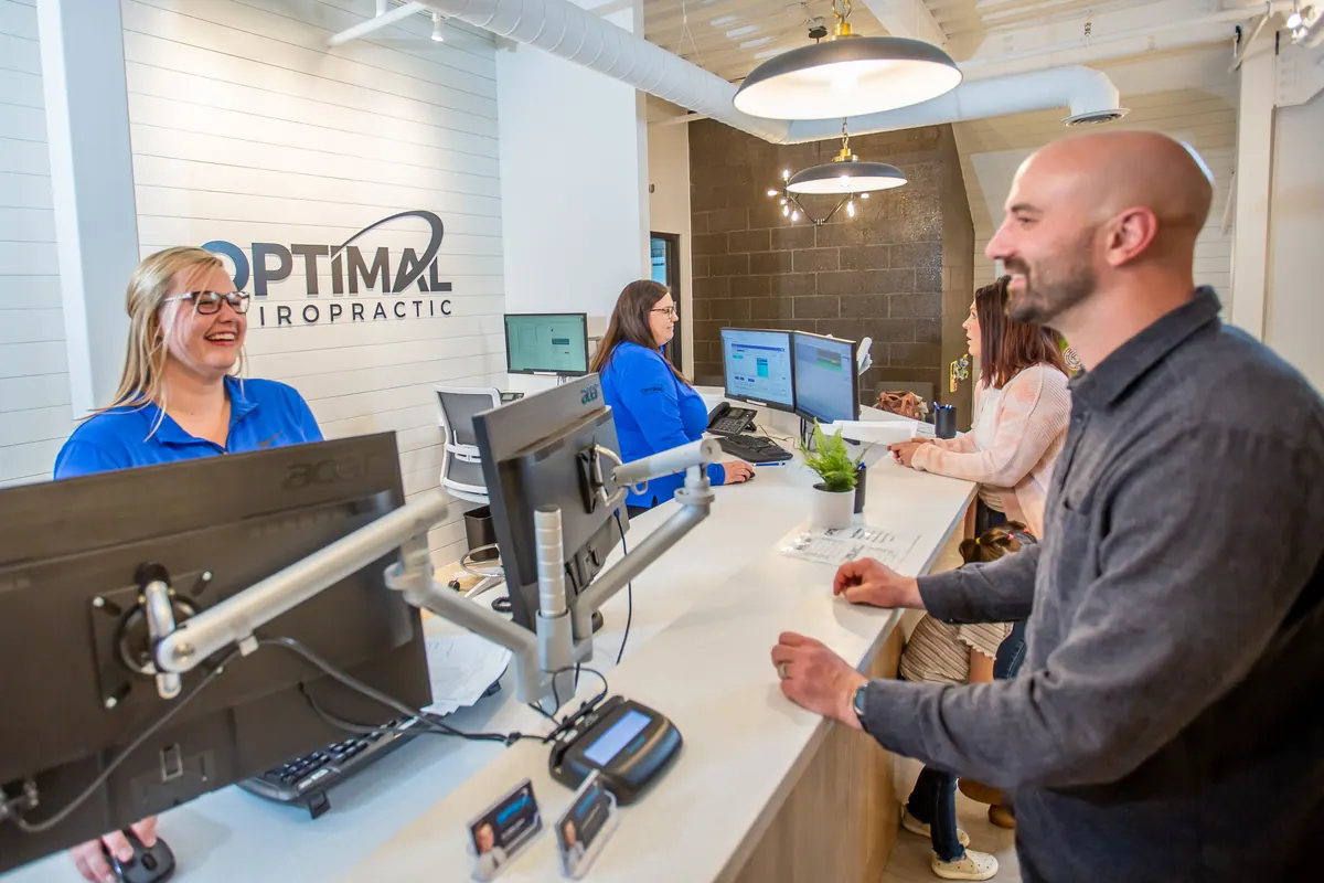 Patient checking in at the Optimal Chiropractic reception desk