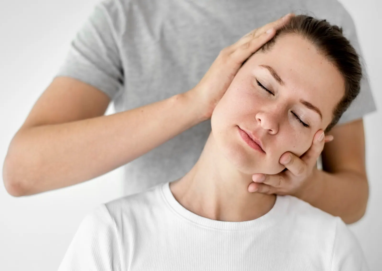 Practitioner gently holding a patient's head and neck