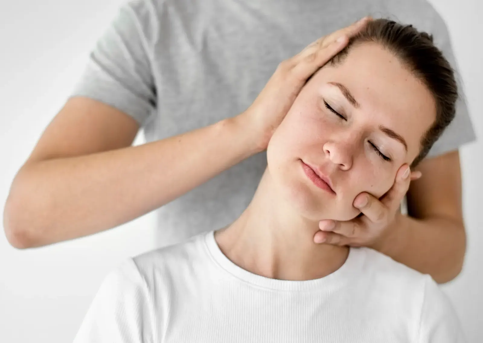 Practitioner gently holding a patient's head and neck
