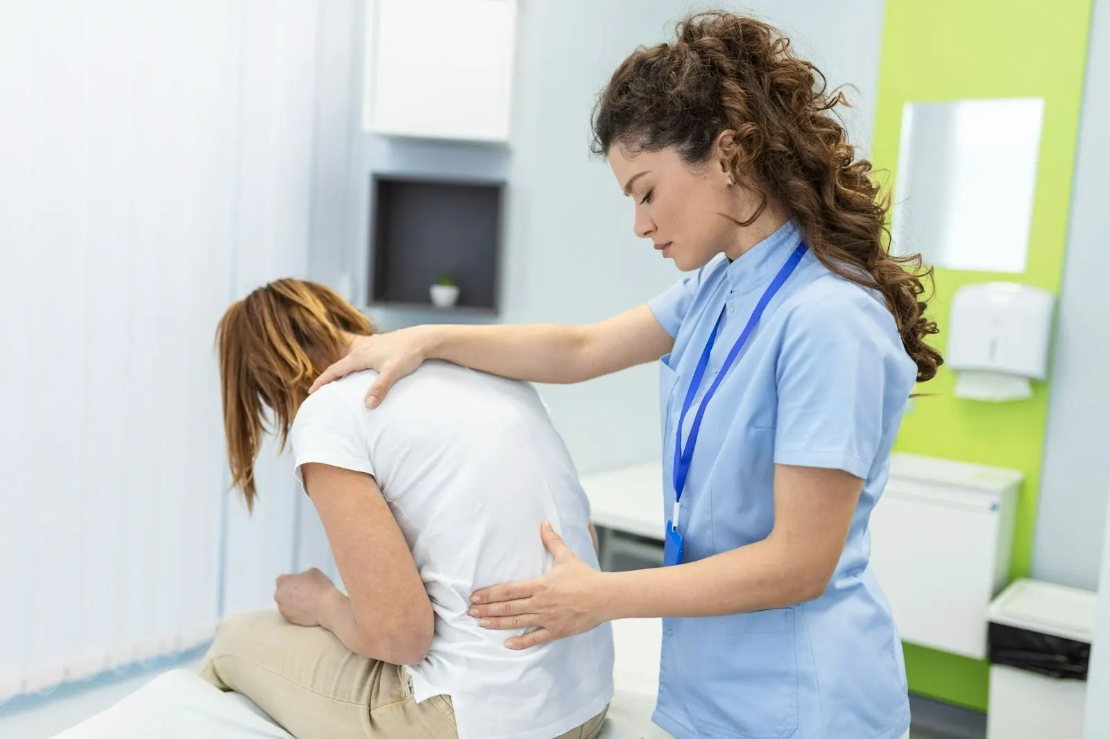 Practitioner examining a seated patient's lower back