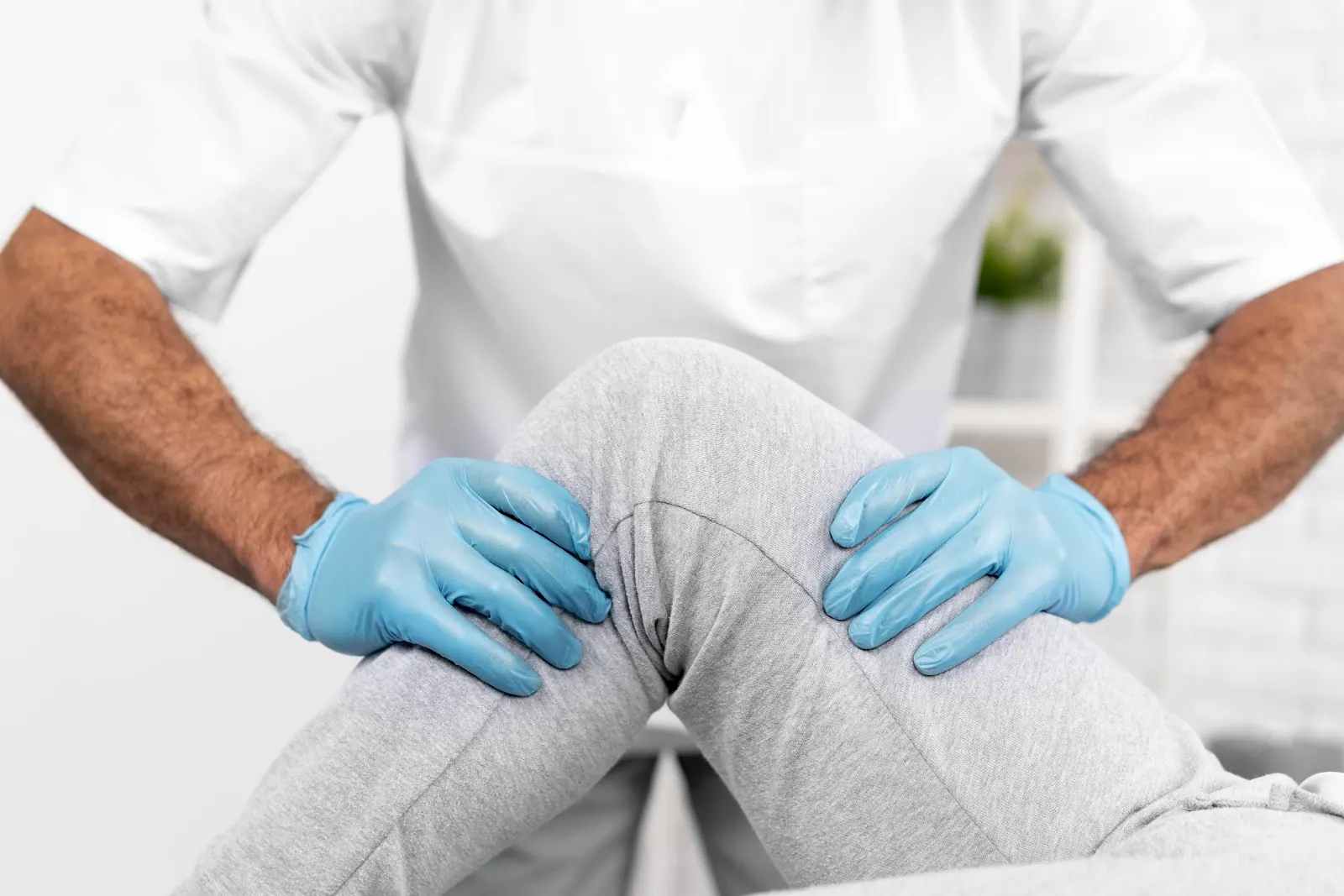 Gloved practitioner examining a patient's knee
