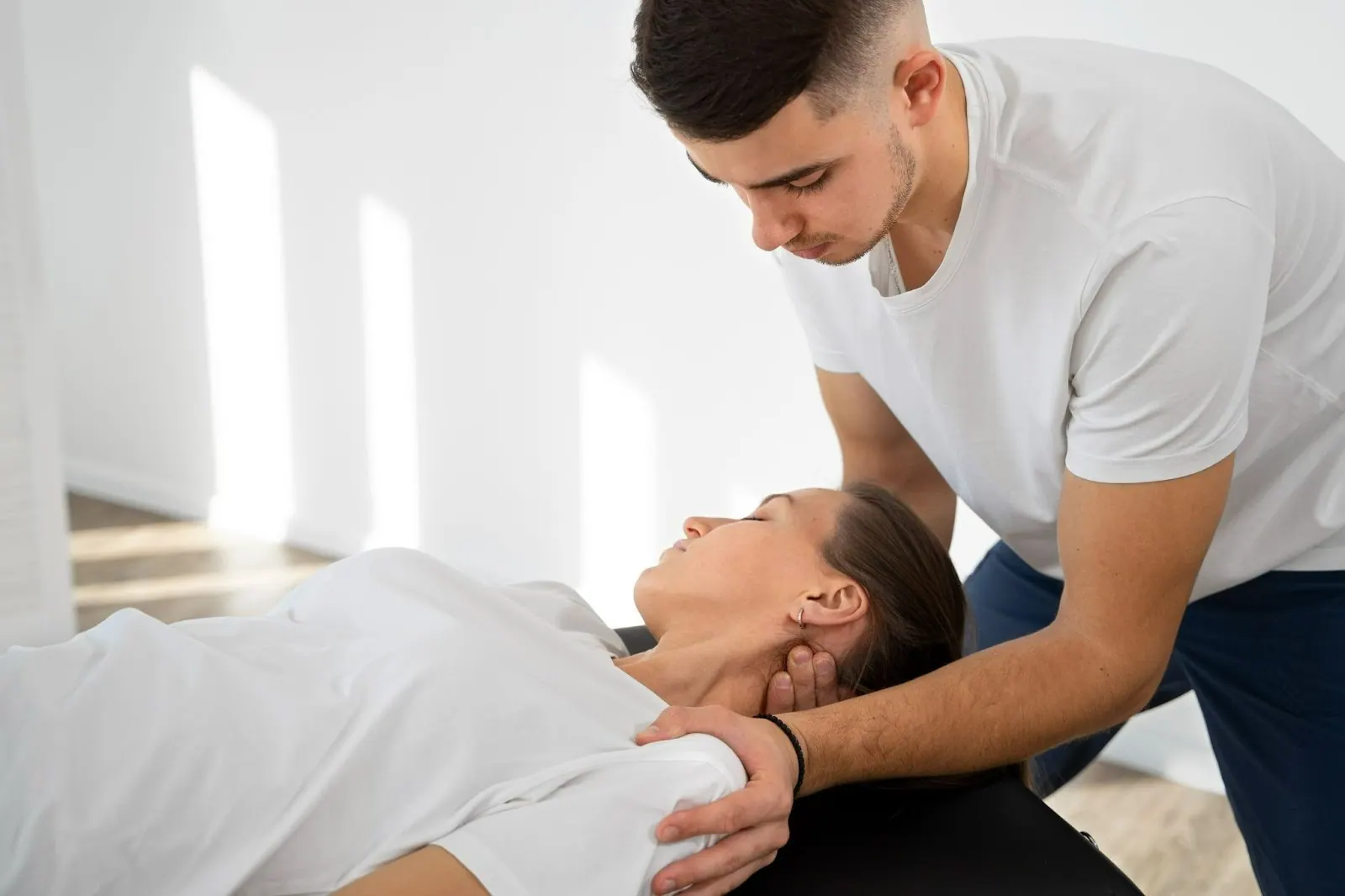 Practitioner treating the neck of a woman lying on a table