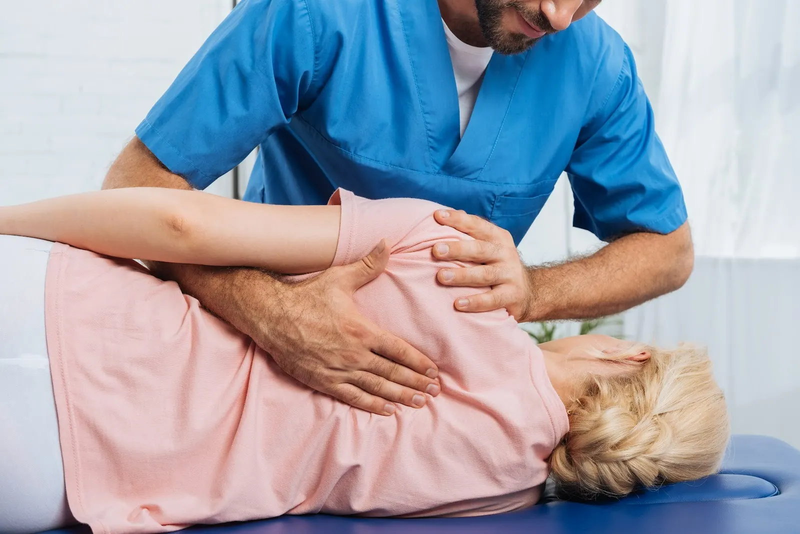 Practitioner treating a patient's shoulder and back as she lies on her side
