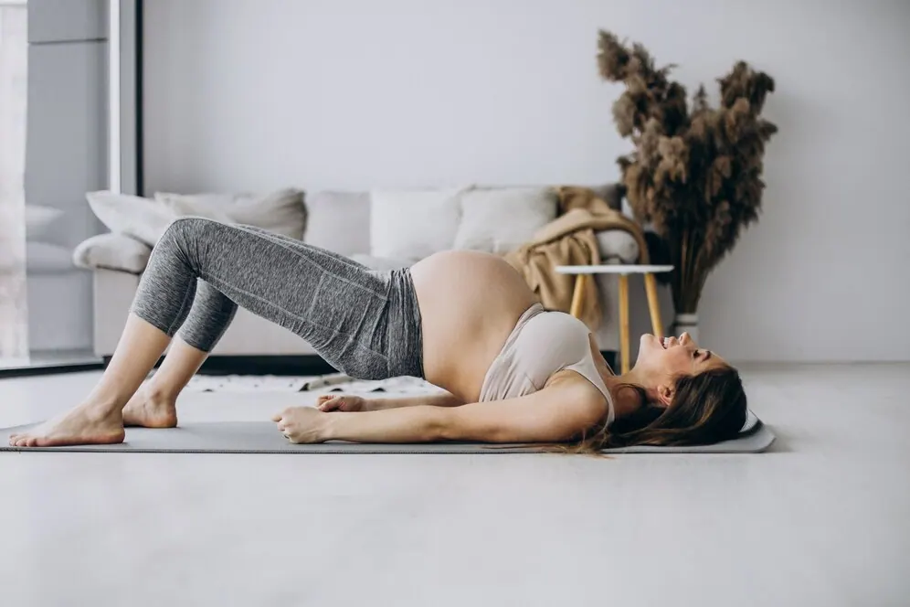 Pregnant woman doing a bridge exercise on a yoga mat at home