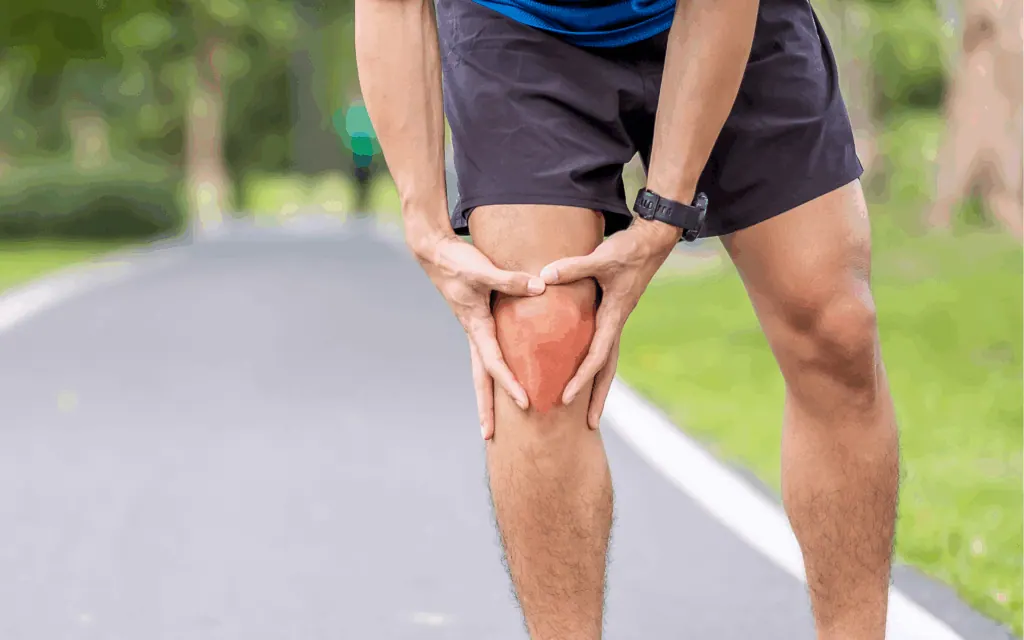 Runner holding his knee with the painful area highlighted on a path
