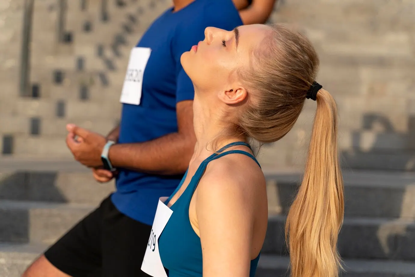 Runner with a race number resting with her eyes closed