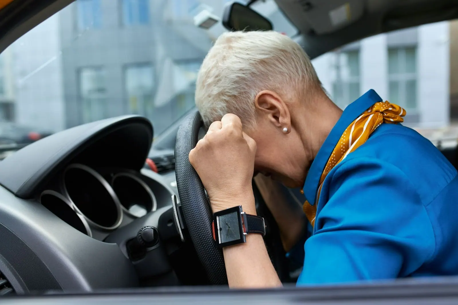 Woman resting her head on a car steering wheel