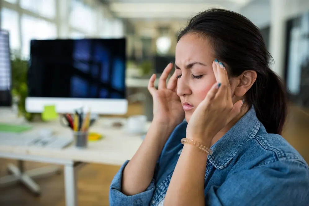 Woman in an office holding her temples
