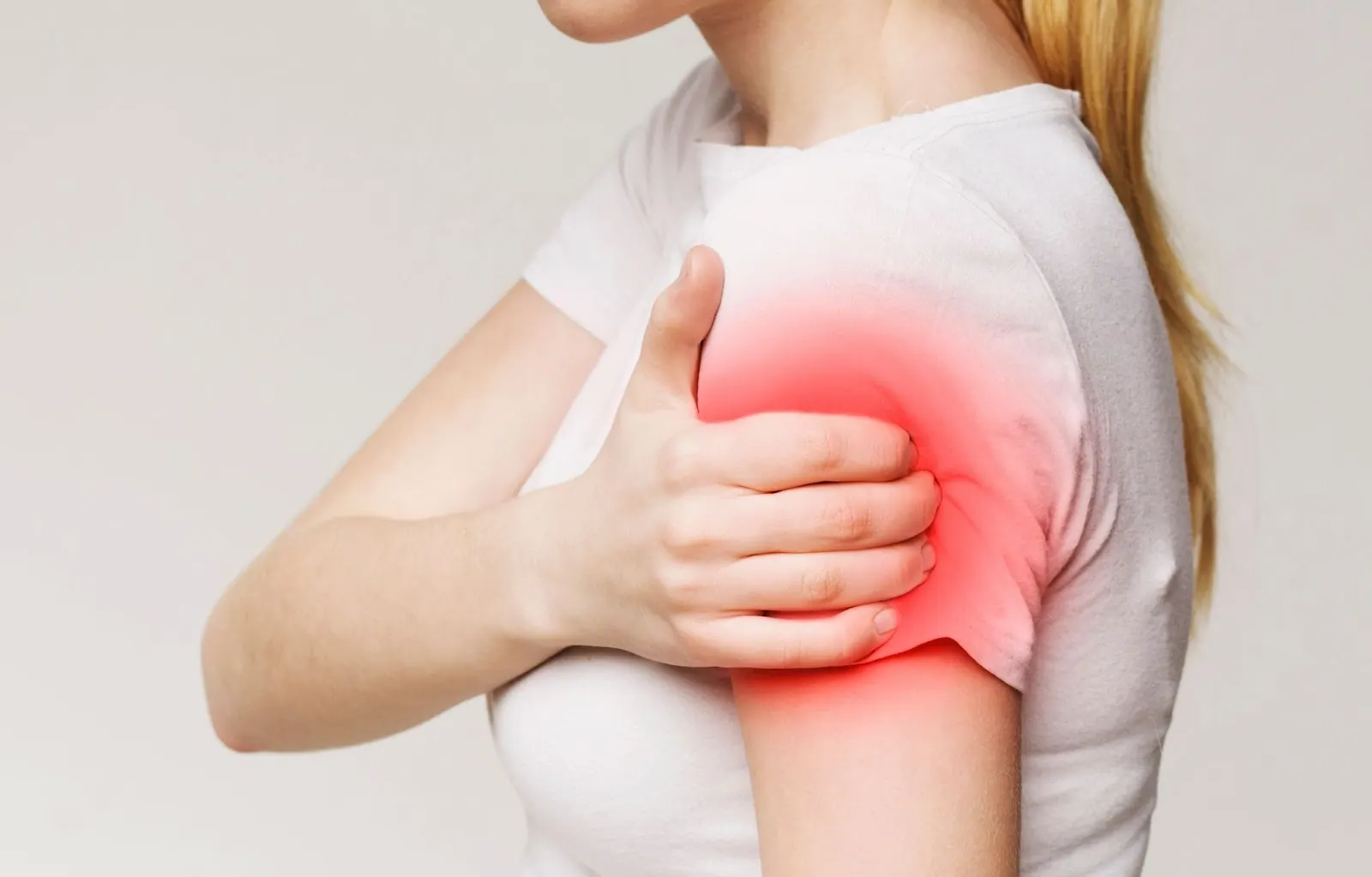 Woman holding her shoulder with the painful area highlighted in red