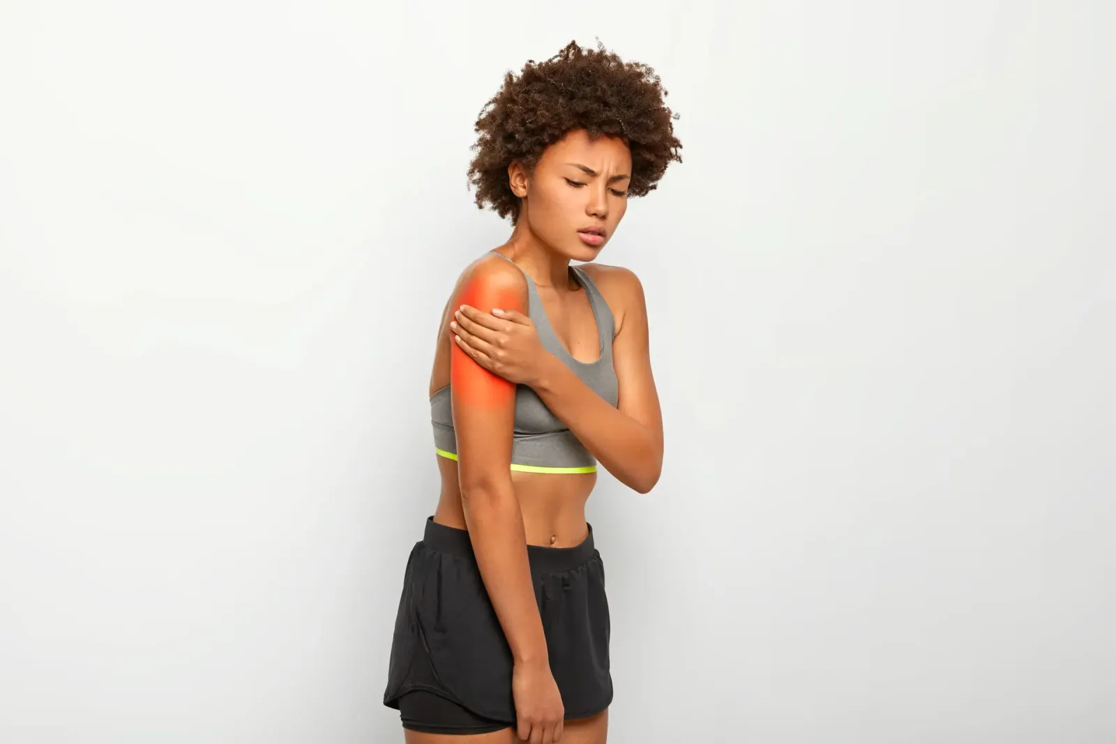 Woman holding her shoulder with the painful area highlighted