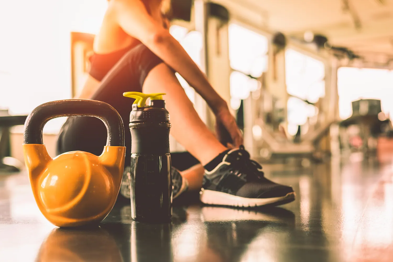 Athlete sitting on a gym floor next to a kettlebell and water bottle