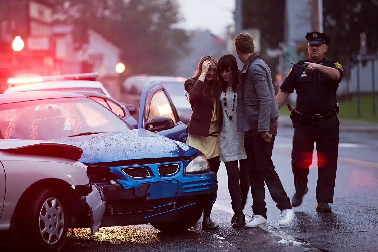 Police officer helping people at a nighttime car accident scene