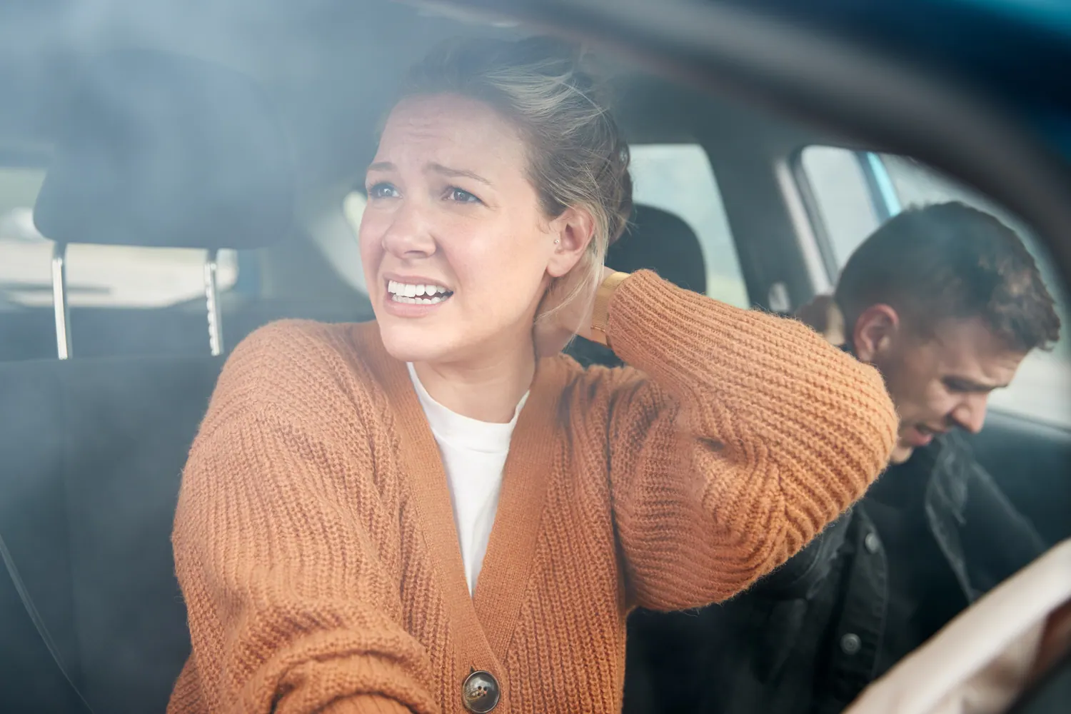 Woman holding her neck in a car after a collision