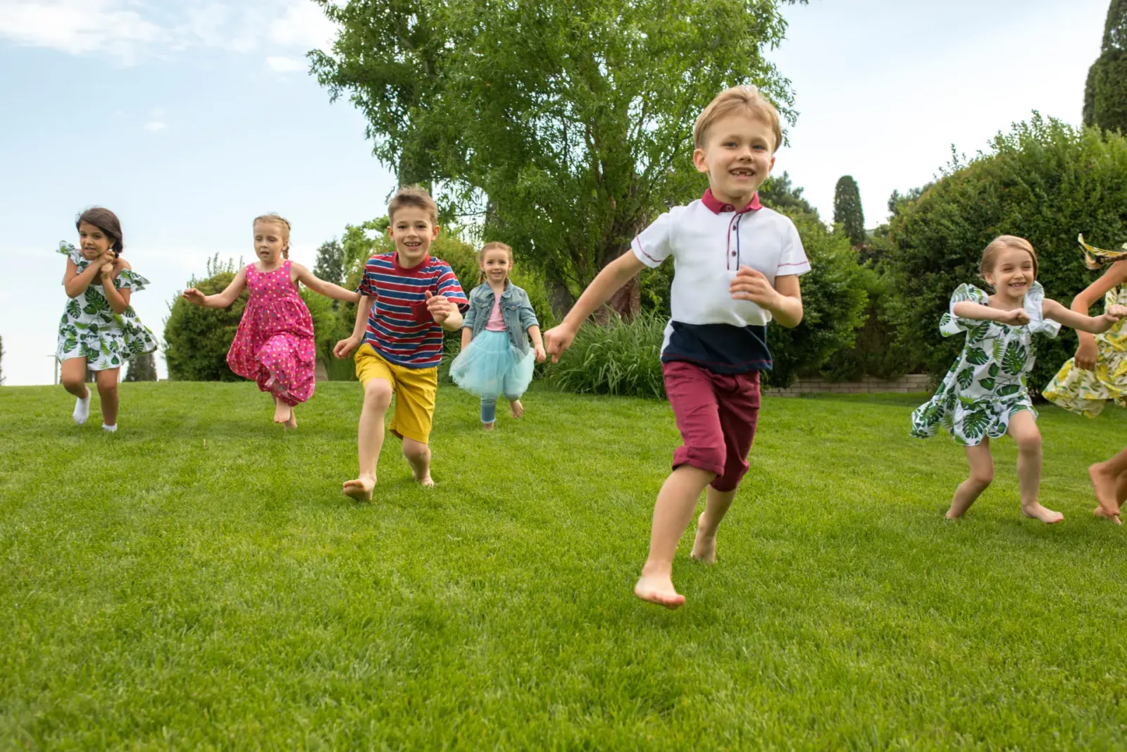 Group of children running across a grassy lawn