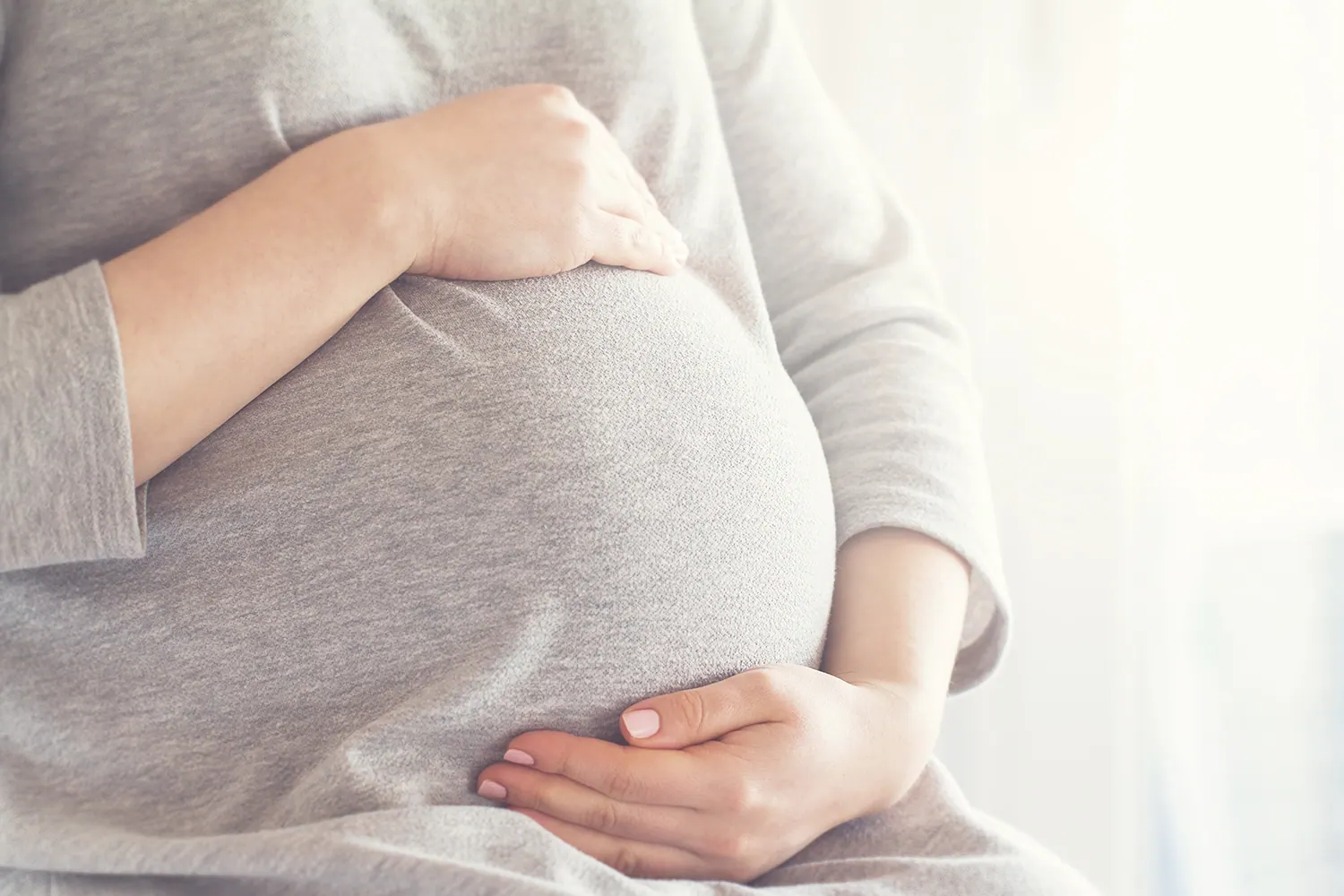 Close-up of a pregnant woman's hands resting on her belly