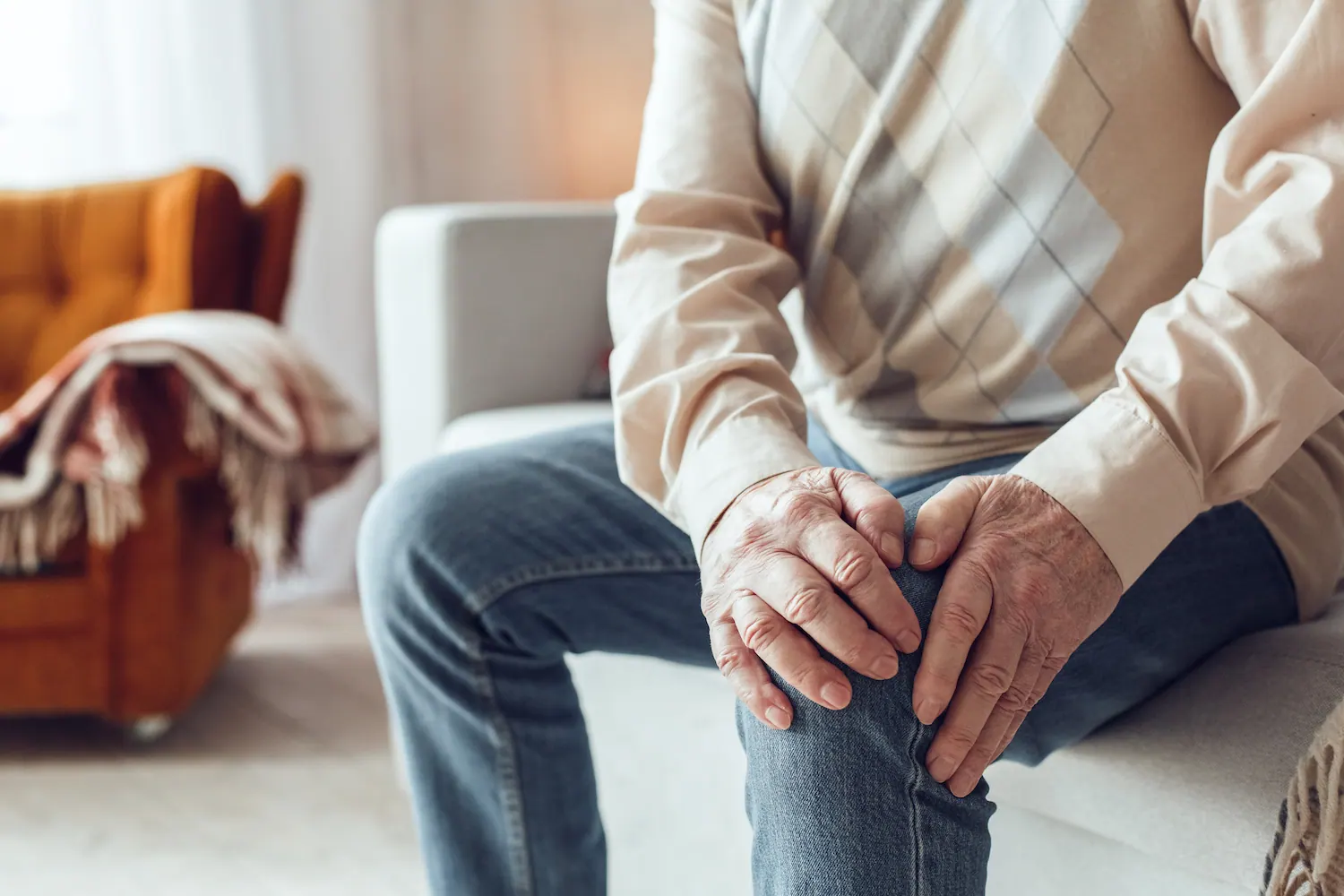 Older man seated and holding his knee