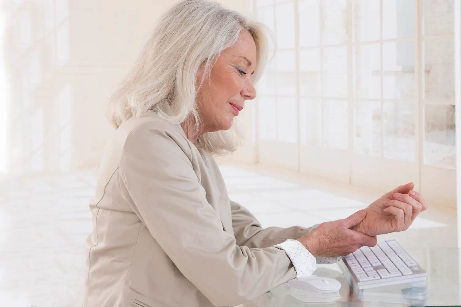 Older woman at a keyboard holding her wrist