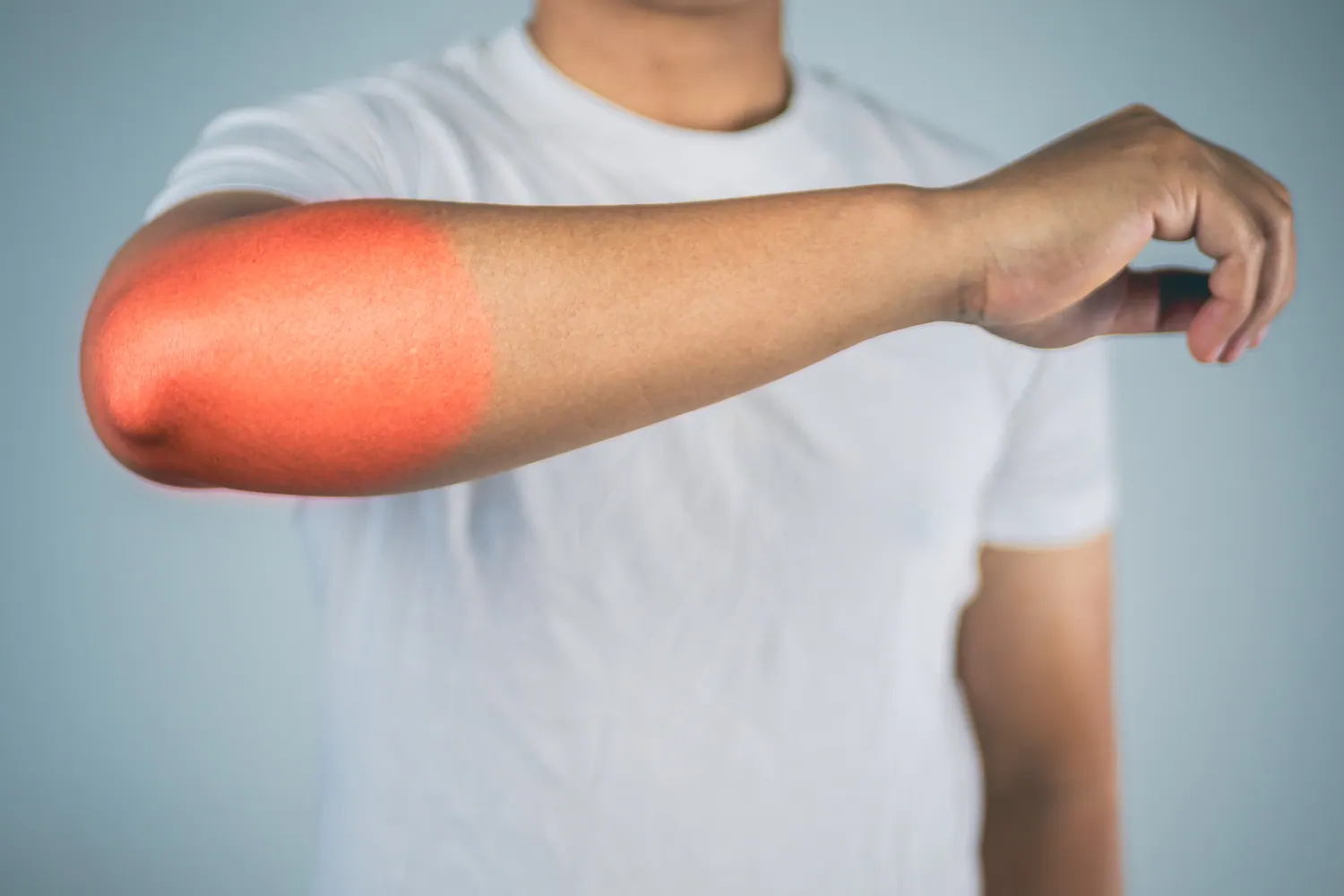 Person holding their arm with the painful elbow highlighted in red