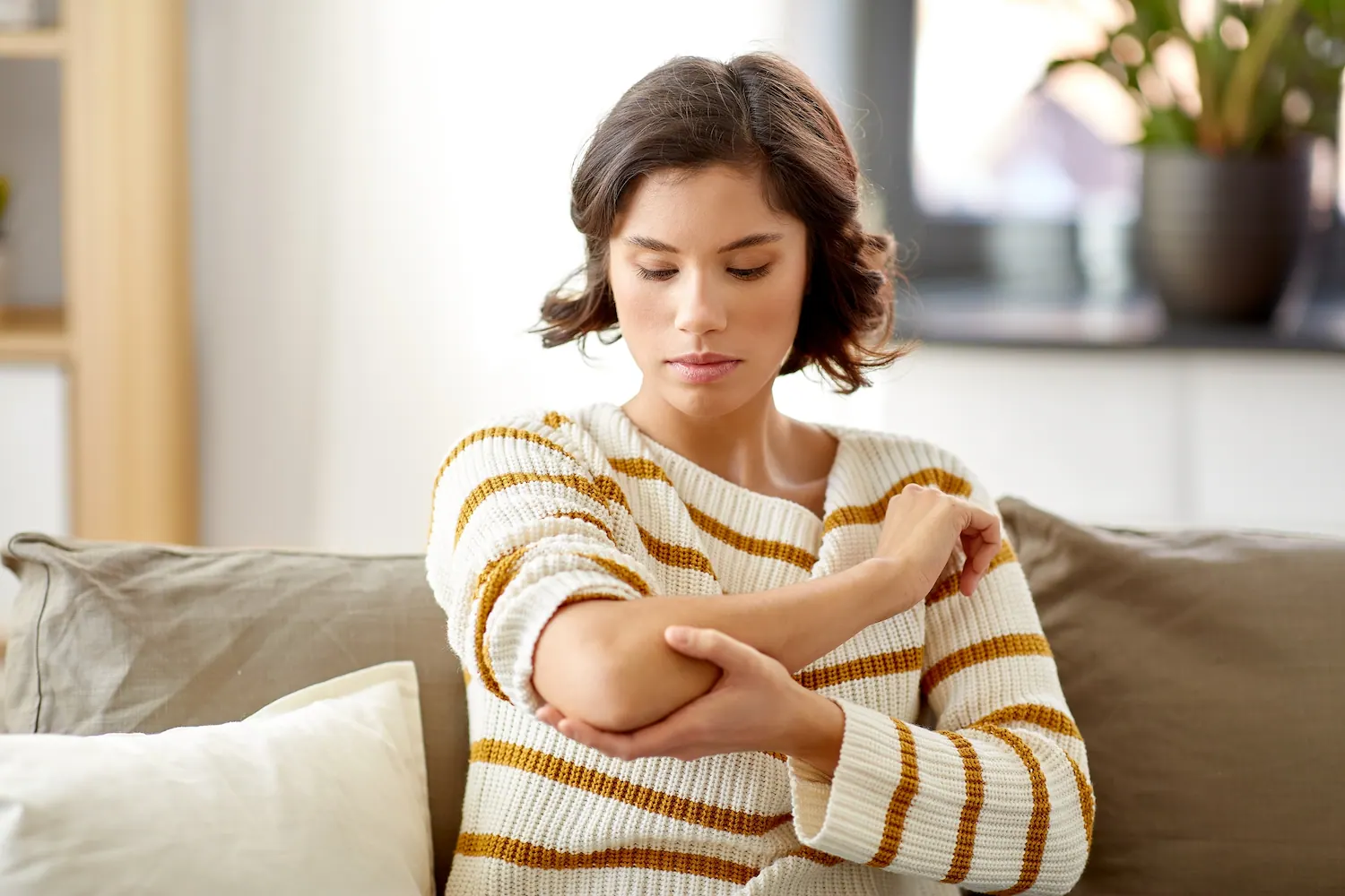 Woman sitting on a sofa holding her elbow