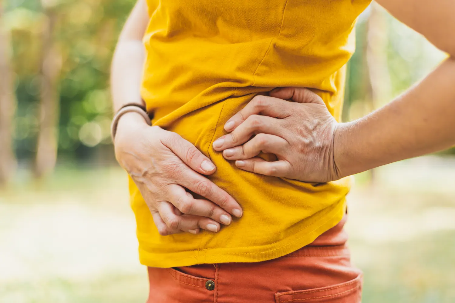 Woman in a yellow shirt holding her hip