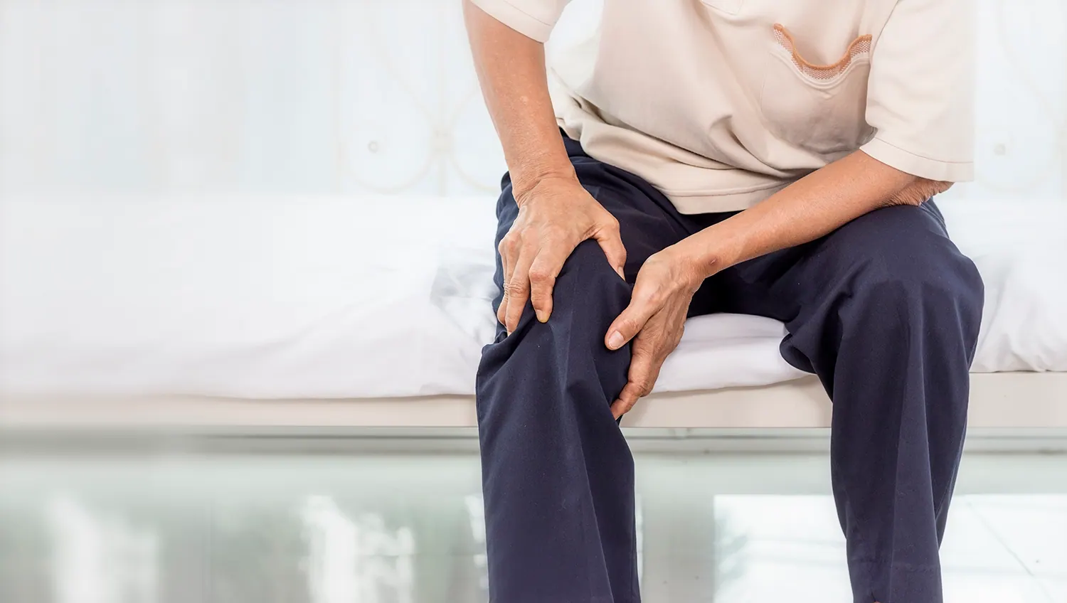Man sitting on a bed holding his legs