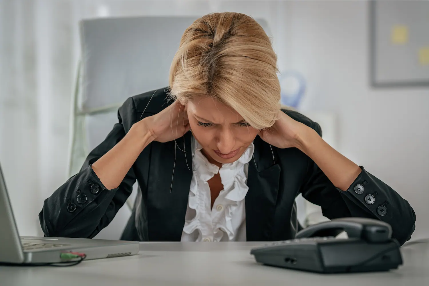 Woman at an office desk holding the back of her neck