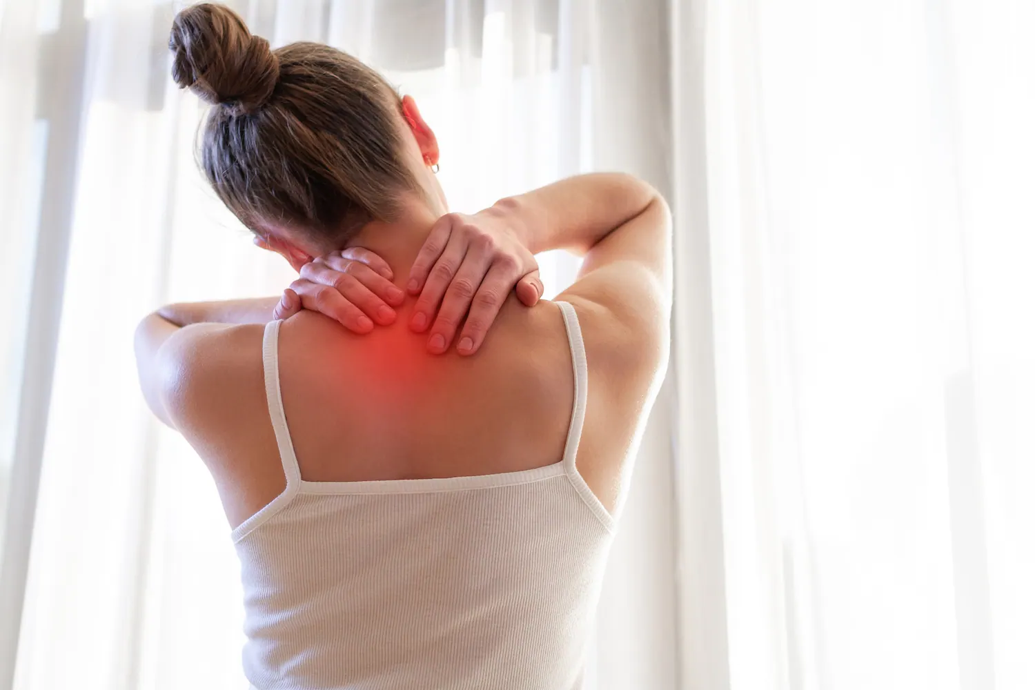 Woman holding the back of her neck with the painful area highlighted in red