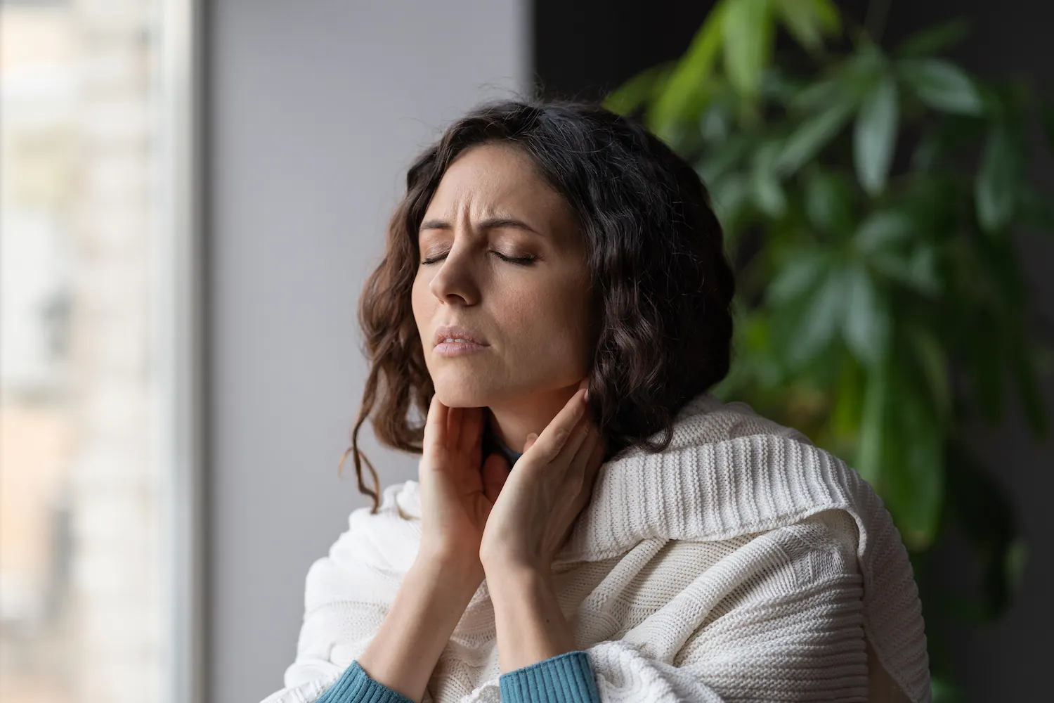 Woman touching her neck and jaw in discomfort