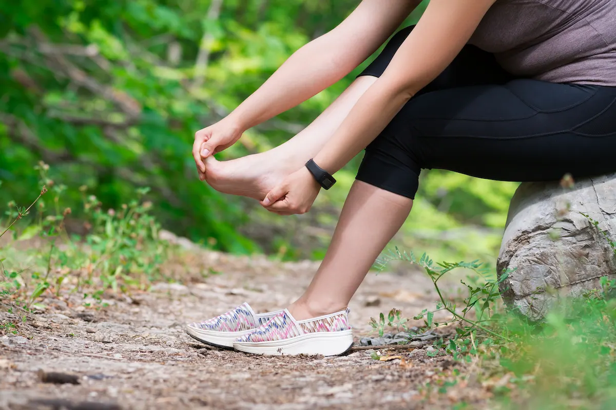 Woman sitting on a trail holding her foot