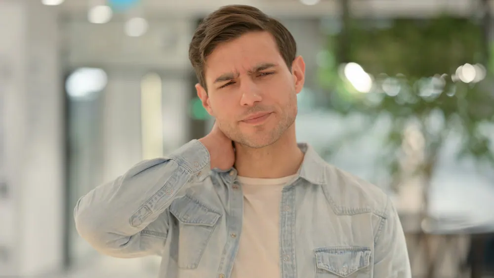 Man rubbing the back of his sore neck