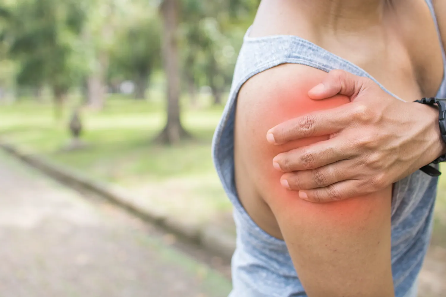Woman holding her shoulder with the painful area highlighted in red